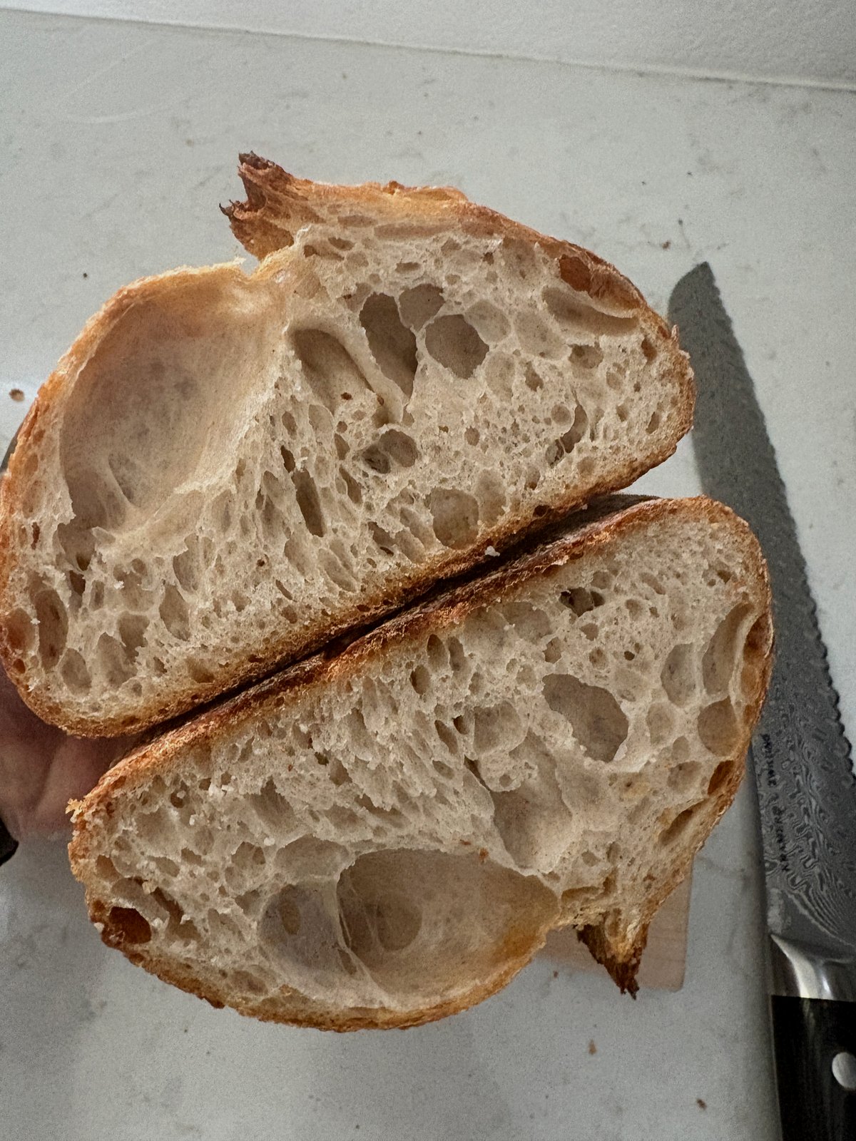 Cross-section of sourdough loaf showing large irregular voids and uneven crumb from weak dough structure