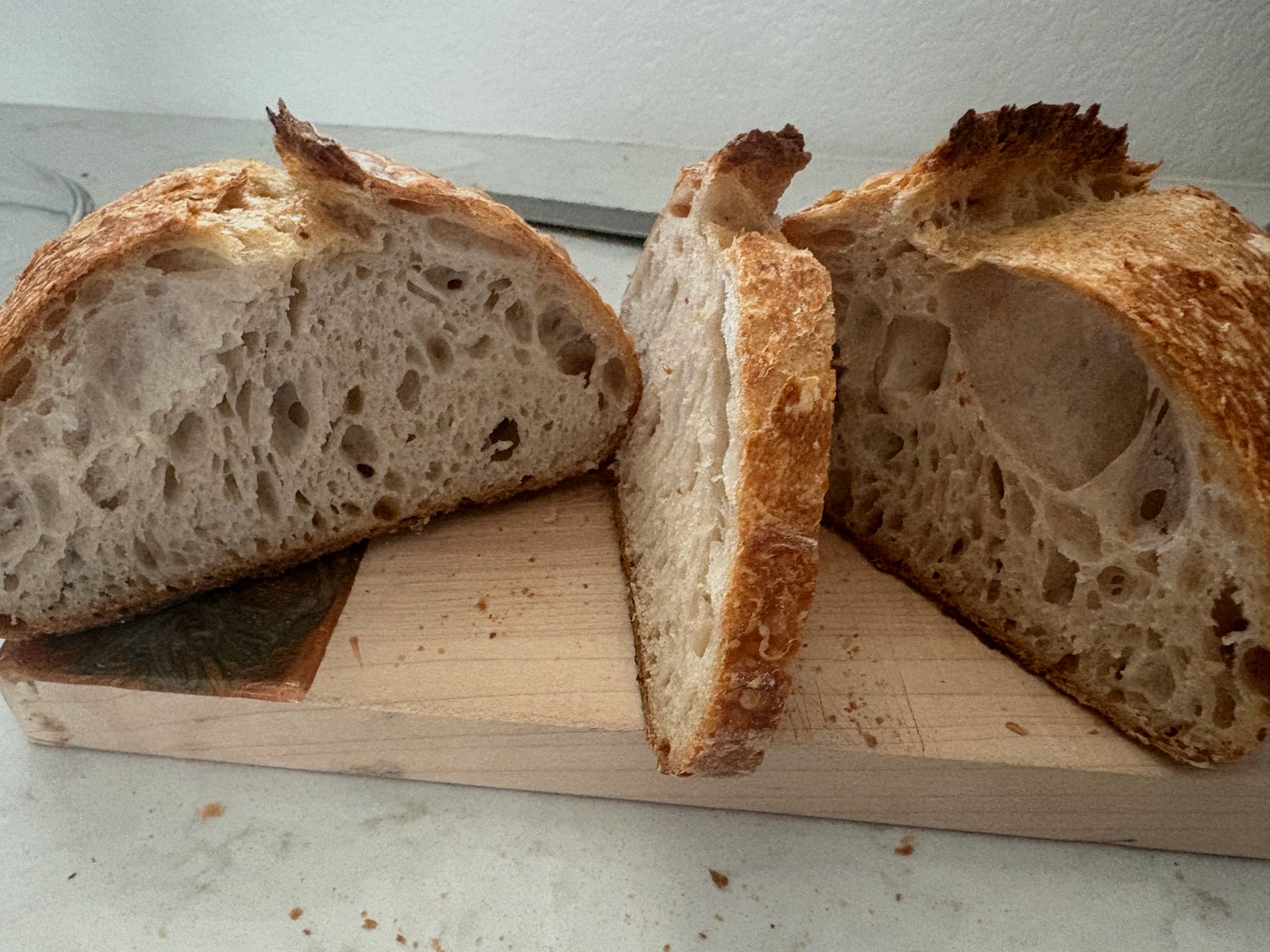 Sourdough loaf with a golden crust and pronounced ear, resting on a wooden cutting board