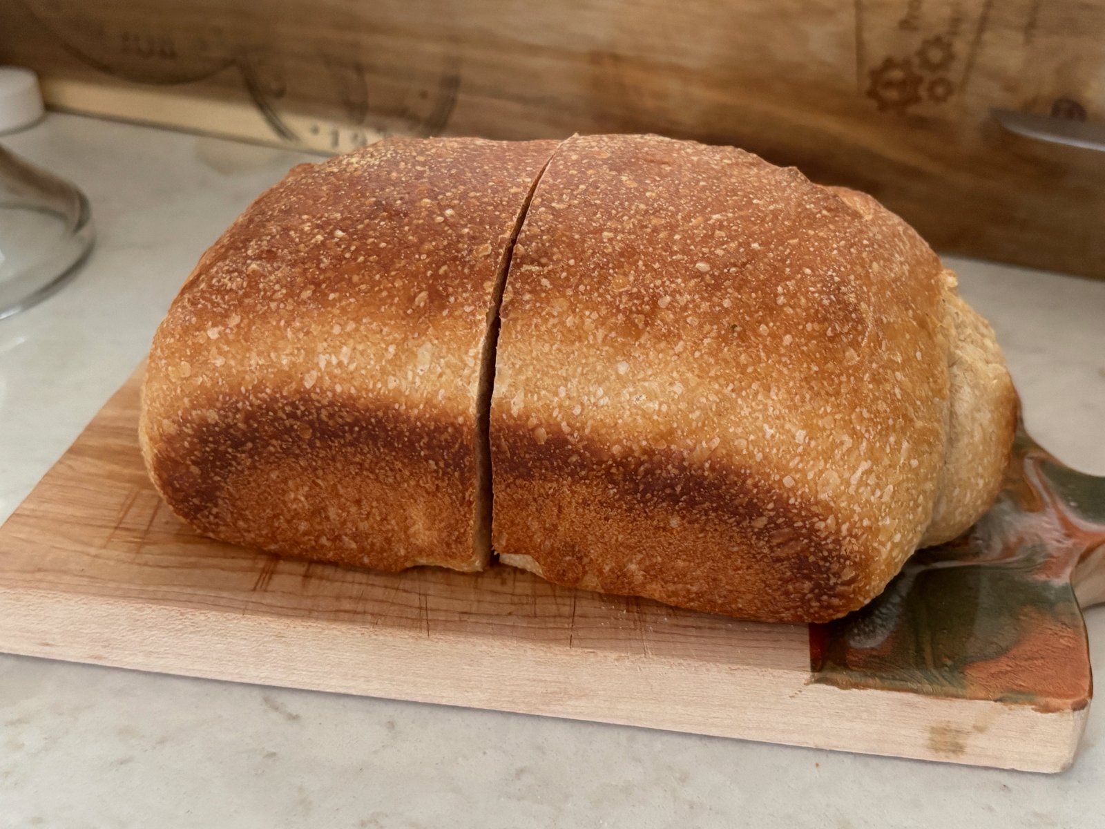 Golden pan loaf of milk sourdough with a center score on a wooden board
